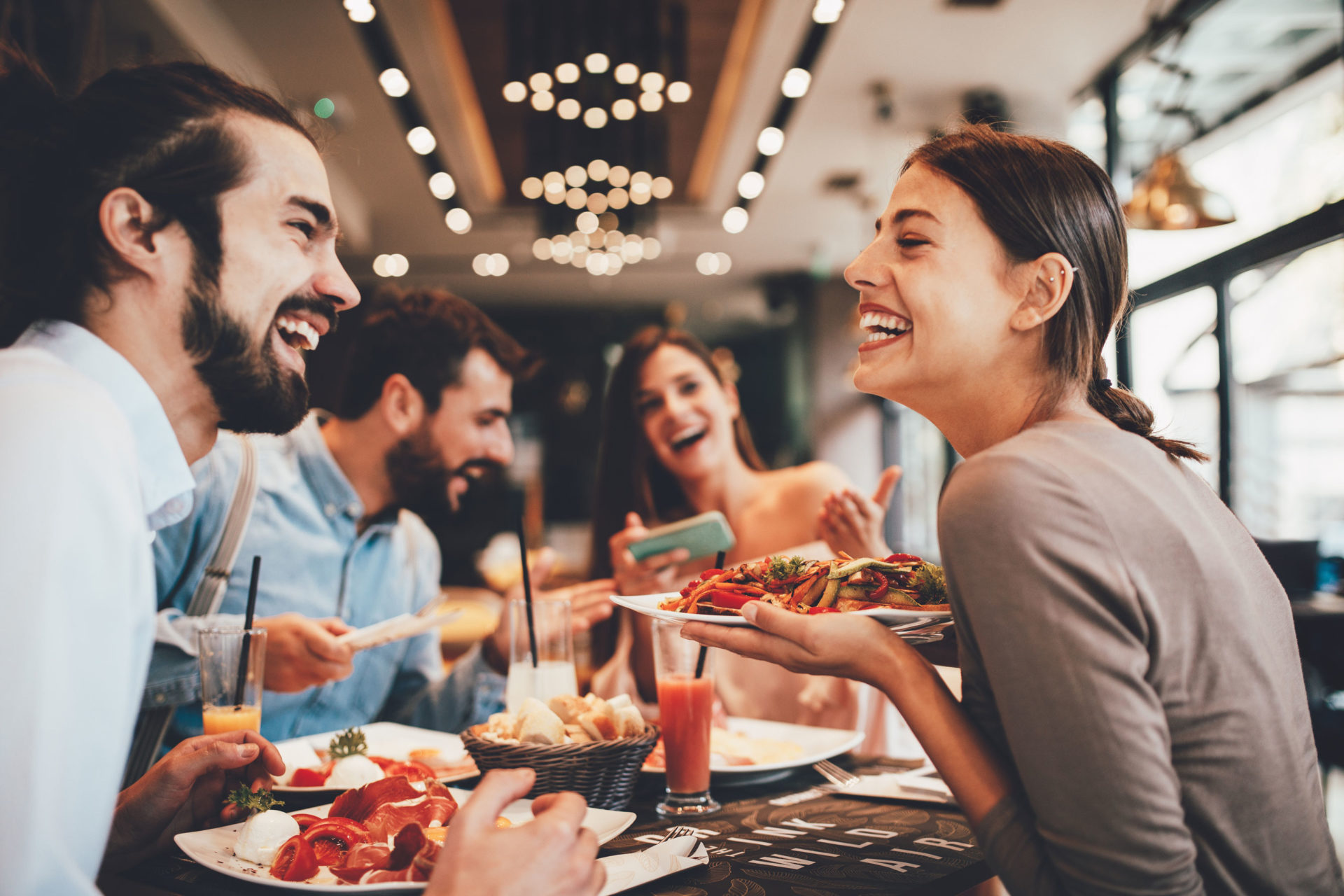 friends smiling and eating together at a restaurant